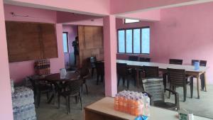 a restaurant with pink walls and tables and chairs at Kedar Kunj in Phata