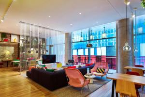 a living room with a black couch and orange chairs at citizenM Austin Downtown in Austin