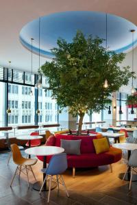a room with a red couch and tables and a tree at citizenM Austin Downtown in Austin