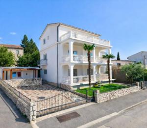 a large white house with palm trees in front of it at Apartments Vukovic in Selce