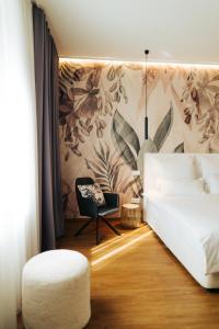 a bedroom with a white bed and a chair at The Kepos Hotel Erlangen in Erlangen