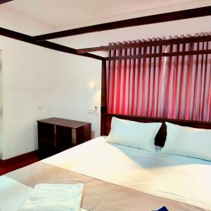 a bedroom with a large bed with a red curtain at Samson & Ruby Villa in Weligama
