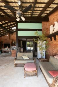 a living room with couches and a ceiling fan at Casa Jataí Guest House in Barra do Sahy