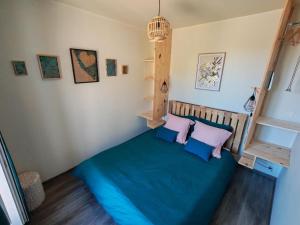 a bedroom with a bed with blue sheets and purple pillows at Cœur de Toucy in Toucy