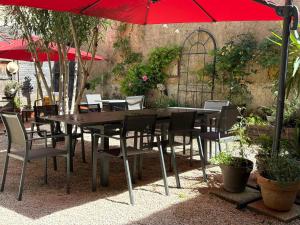 a wooden table and chairs with a red umbrella at Le Clos d'Orange - Hotel & ville de Provence in Orange +62 photos