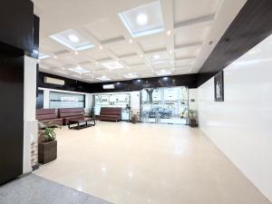 an office lobby with couches and tables and windows at Malaysia inn in Chennai