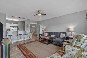 a living room with a couch and a kitchen at Wicked Fun at Windswept Ridge in Corolla