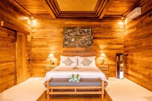 a bedroom with a bed in a room with wooden walls at Kubu Tama Villa in Tegalalang