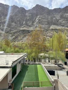 a house with a green lawn in front of a mountain at Pak Himalaya Hotel Kachura in Ponedas