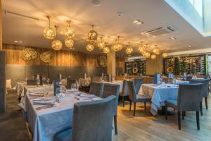 a dining room with tables and chairs and chandeliers at Alpinresort ValSaa - Adults Only in Saalbach-Hinterglemm
