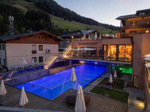 a hotel with a swimming pool in front of a building at Alpinresort ValSaa - Adults Only in Saalbach-Hinterglemm