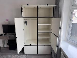 a white cabinet with black shelves in a room at The Villas in Rock Ferry