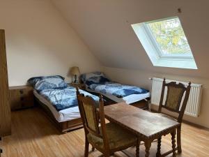a attic room with two beds and a table and a window at Valéria Vendégház in Budakalász