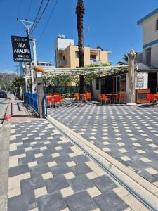 a street with tables and chairs and a sign at Rooms and Apartments Analipsi in Shëngjin