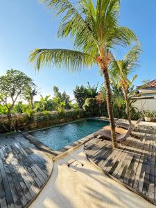 a swimming pool with a palm tree next to a house at Sedana Cottage in Canggu