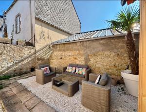 a patio with two couches and a palm tree at Maison du Caboteur de La Baule, Centre & plage à pied, Patio cosy, 8 pers in Le Pouliguen