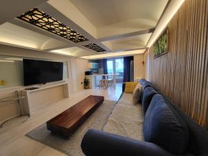 a living room with a large couch and a tv at Jeju Its Hill Pension in Jeju