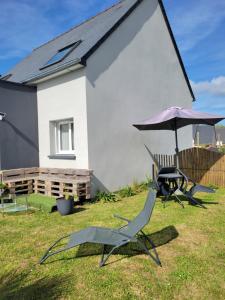 a table and two chairs and an umbrella in a yard at chambre d'hôte in Pleslin-Trigavou