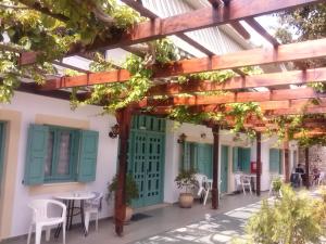 a patio with a green door and tables and chairs at G&P Rooms Matala in Matala