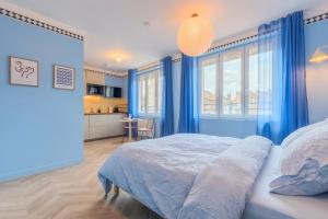 a bedroom with blue walls and a large bed at Le Cottage du Louvre in Lens