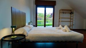a bedroom with two beds and a table and a window at Ecopausa Somió - Gijón in Gijón