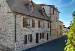 an old stone building with brown windows and a driveway at La p'tite Maison in Vitrac