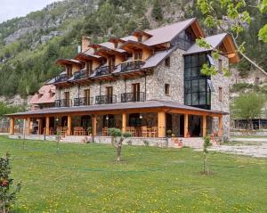 a large house on a field in front of a mountain at Golden Villa in Theth