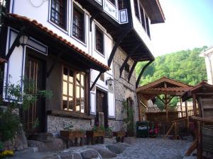 un ancien bâtiment avec une passerelle en pierre devant lui dans l'établissement Popsokol House, à Bratsigovo