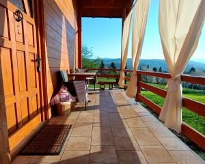 a porch with a door and a table and a view at Lorraine's cabin Plitvice in Drežnik Grad