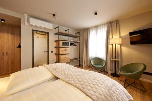 a bedroom with a bed and two green chairs at Hotel Zeltinger-Hof - Gasthaus des Rieslings in Zeltingen-Rachtig