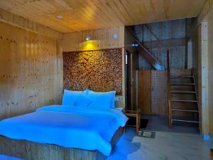 a bedroom with a bed with a wooden wall at Riverside Bliss Cottages in Gushaini +36 photos