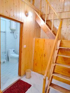 a bathroom with a wooden staircase and a toilet at Riverside Bliss Cottages in Gushaini