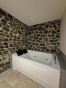 a bath tub in a bathroom with a stone wall at Studio Spa Murol Centre Relaxation in Murol