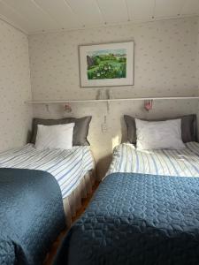 a room with two beds and a picture on the wall at The Hunters Hill - Cosy private forest retreat in Brålanda