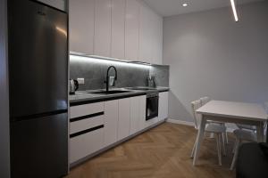 a kitchen with white cabinets and a stainless steel refrigerator at Villa Billa in Tirana