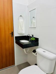 a bathroom with a white toilet and a sink at Voer Jequitibá Hospedaria in Jequitibá