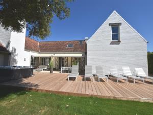 a wooden deck with white chairs and a building at Luxury Villa in Sint-Idesbald with Jacuzzi in Sint-Idesbald