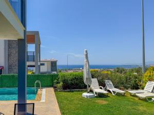 a yard with chairs and an umbrella and a pool at Villa Elite in Kuşadası