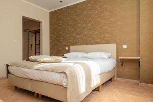 ein Schlafzimmer mit einem großen Bett mit weißen Laken und Kissen in der Unterkunft Hotel Amary in Maldegem