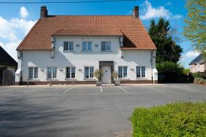 ein großes weißes Haus mit Parkplatz in der Unterkunft Hotel Amary in Maldegem
