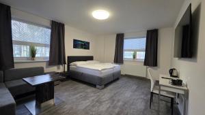a bedroom with a bed and a couch and a table at Apartmány Koruna in Ostrava
