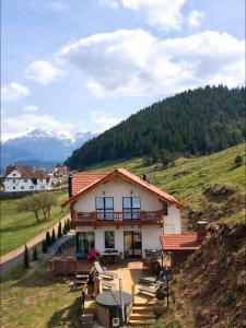 a house on a hill with people sitting in front of it at Casa de Sub Munte Cozy Chalet in Fundata