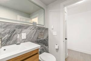 a white bathroom with a sink and a mirror at Stunning Bay Views | Beach Access - Deck - Parking in Provincetown +30 photos