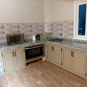 a kitchen with white cabinets and a microwave at Villa Yassine in Mirleft