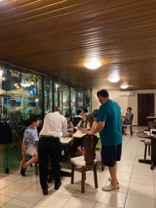 a group of people sitting at tables in a restaurant at Hotel São Luiz in São Gabriel