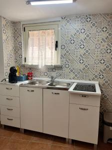 a kitchen with white cabinets and a sink and a window at HeraDea in Crotone +21 photos