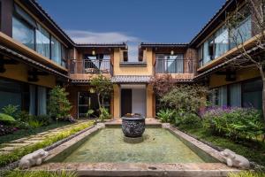 a house with a fountain in the middle of a yard at Aofeng Tangquan Secluded Villa in Jianchuan