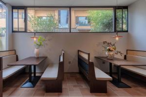 a restaurant with two tables and benches and windows at Aofeng Tangquan Secluded Villa in Jianchuan