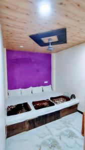 a bed in a room with a purple wall at Jay shree Kedar room in Ujjain +2 photos