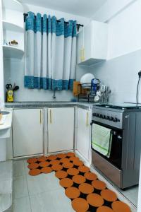 a kitchen with a stove and a rug on the floor at Pearl Homes Nanyuki in Nanyuki +3 photos